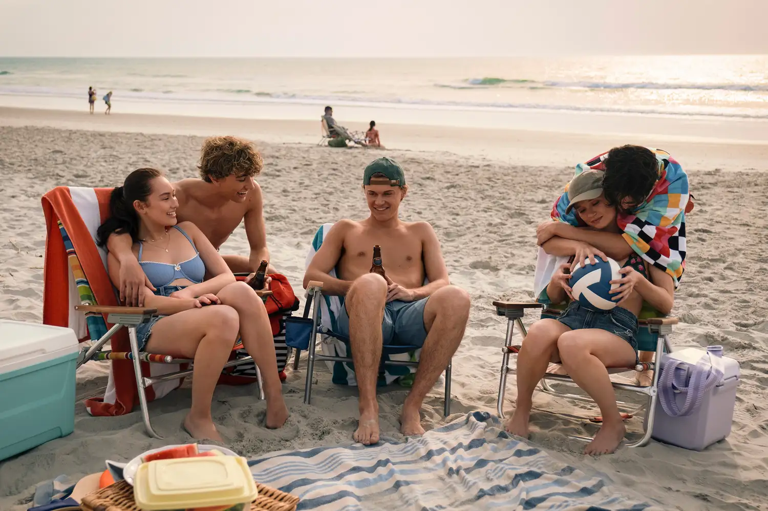 A group of young people relaxing and playing volleyball on a sunny beach.