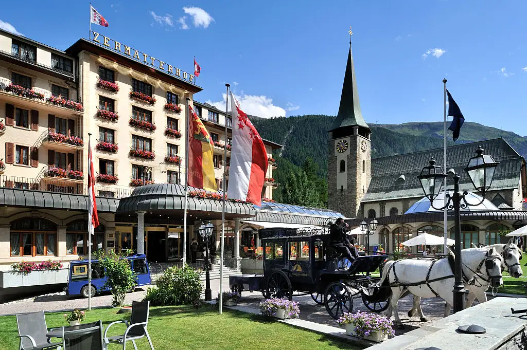 Traditional horse-drawn carriage in front of a church in Zermatt, Swiss Alps.