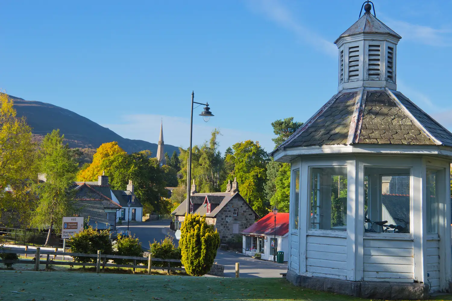 A peaceful townscape of Braemar village with a gazebo in the foreground and hills behind.
