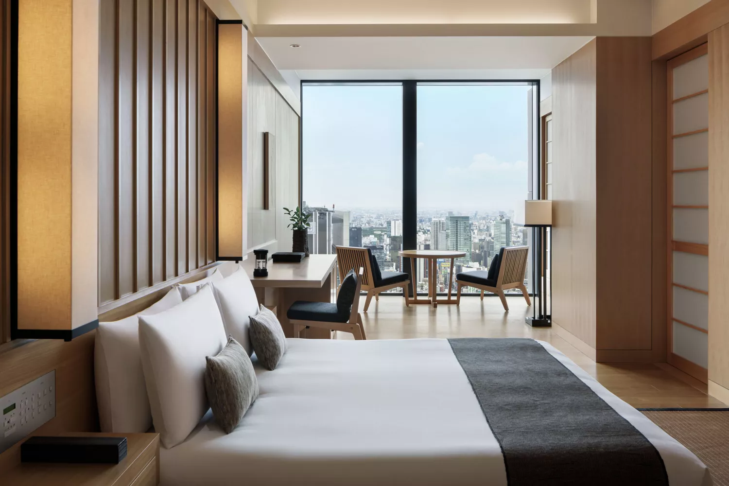 Minimalist guest room at Aman Tokyo with large windows and wooden accents.