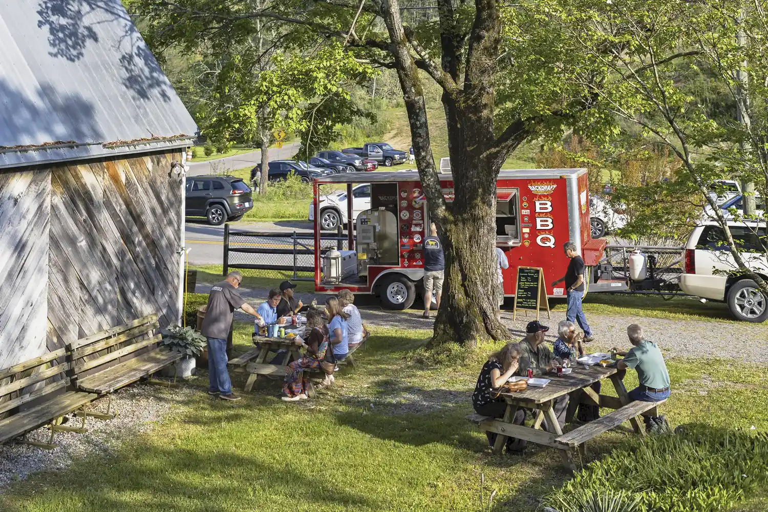 A crowd of attendees gathered around a red BBQ food truck at the Carter Family Fold's 50th anniversary.