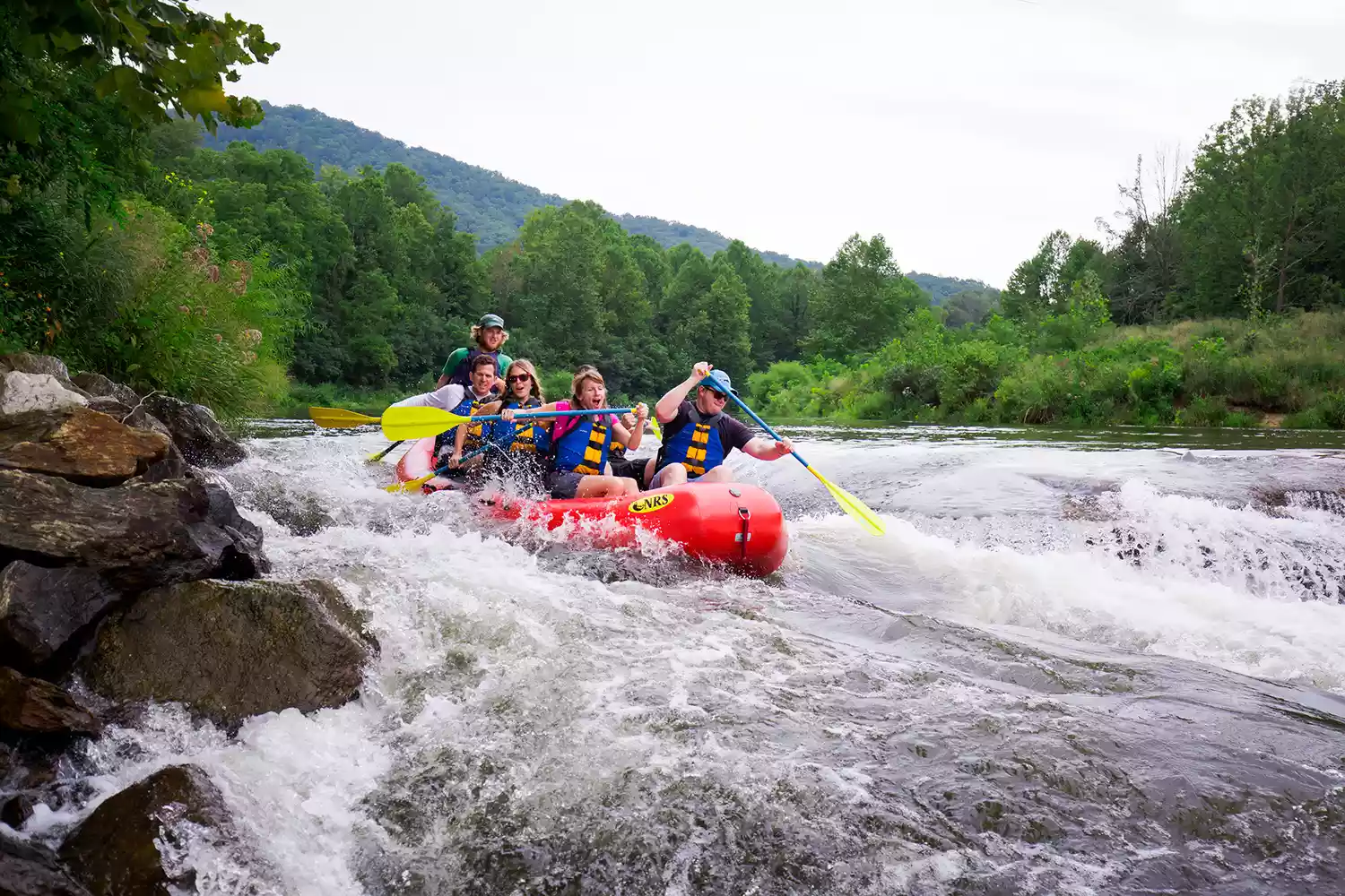 A group of people white water rafting down the scenic Tuckasegee River.