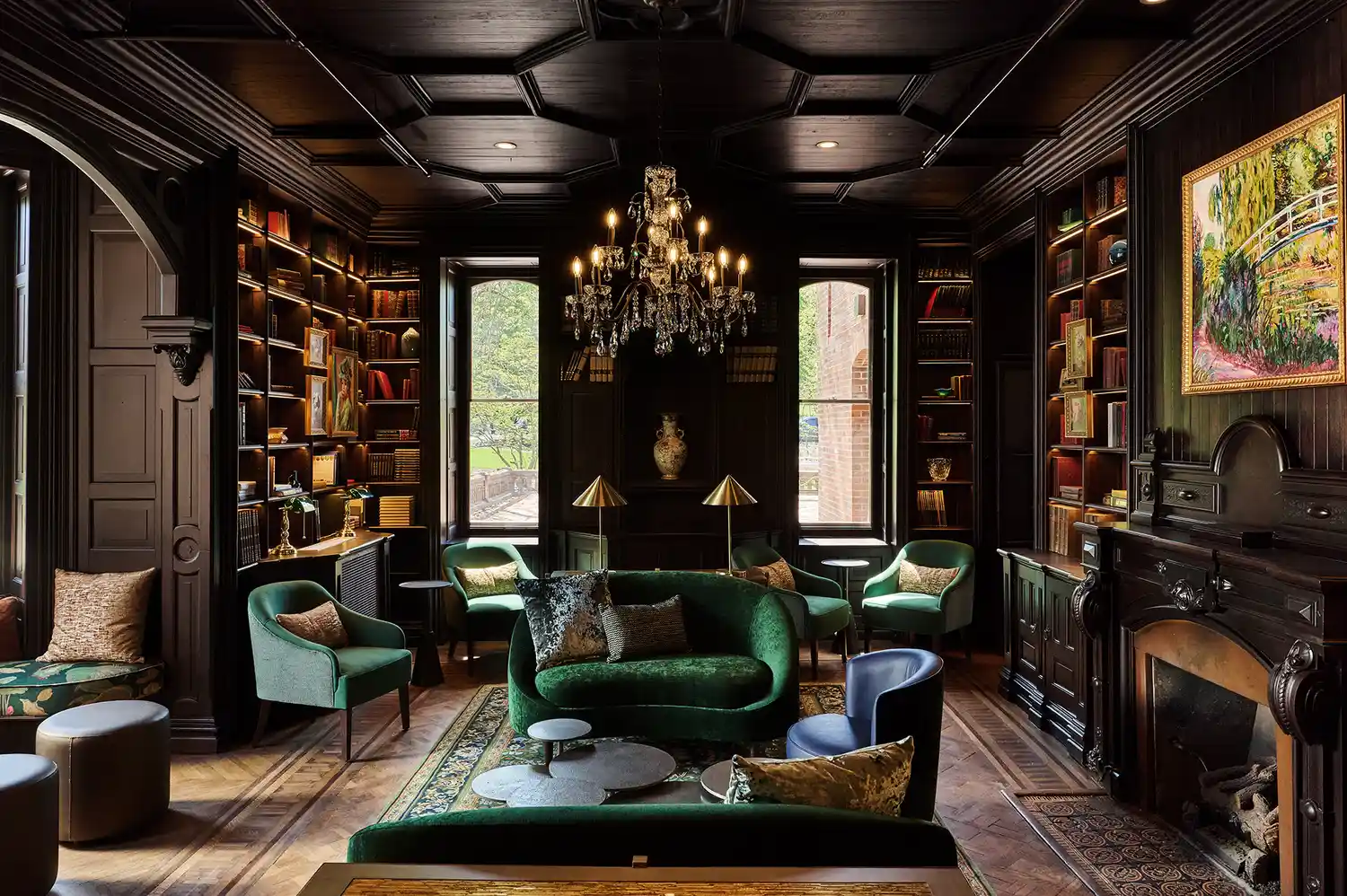 A cozy library room with wall-to-wall books, a fireplace, and plush seating.