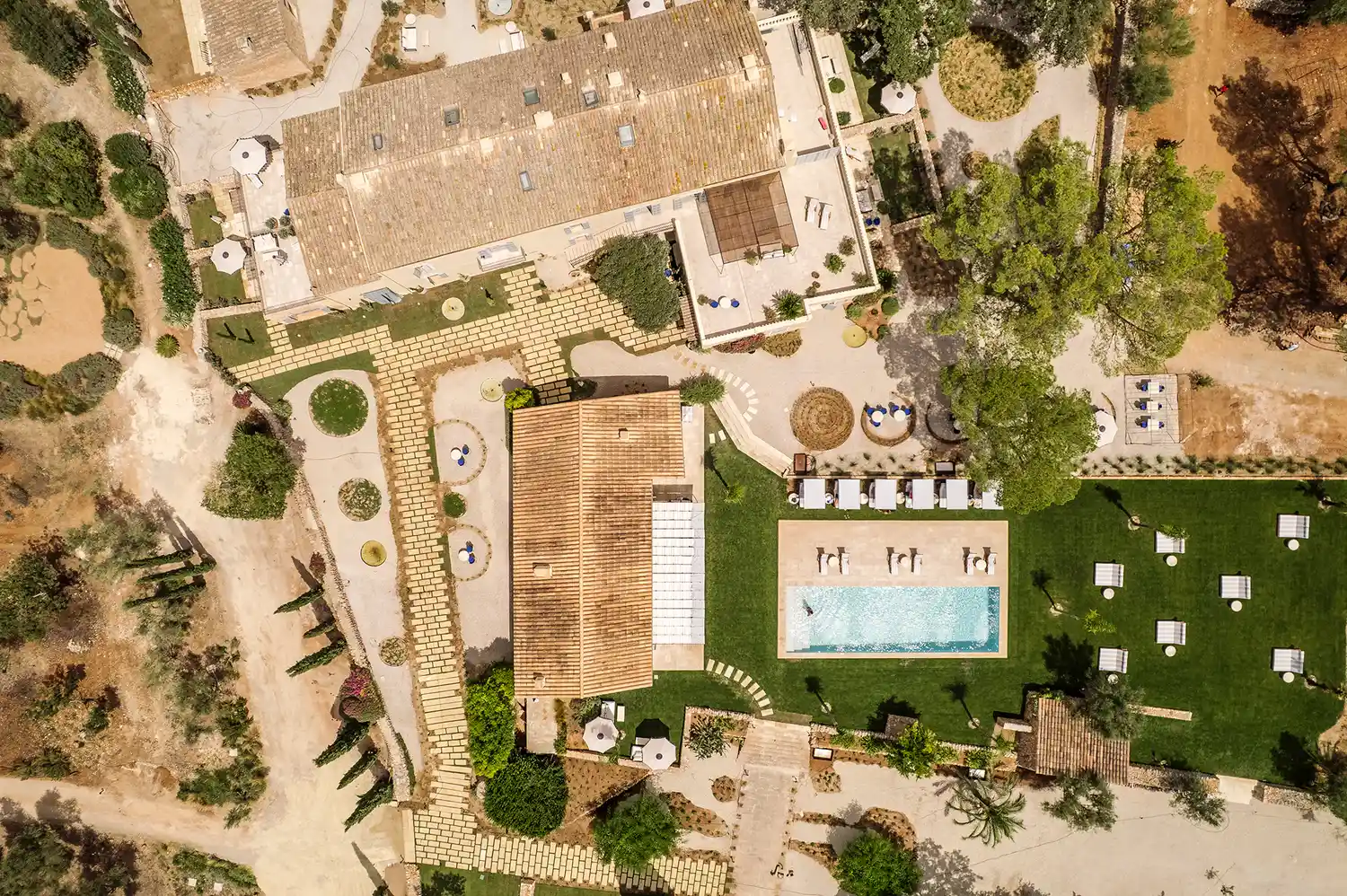 Aerial view of the Son Xotano estate showing the stone buildings, swimming pool, and lush green grounds.