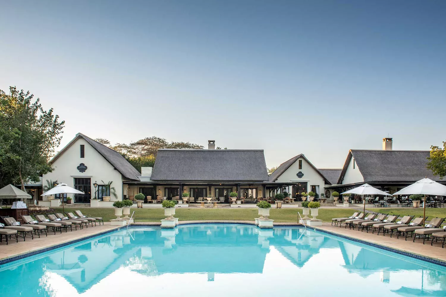 Outdoor swimming pool at The Royal Livingstone overlooking the Zambezi River at sunset.