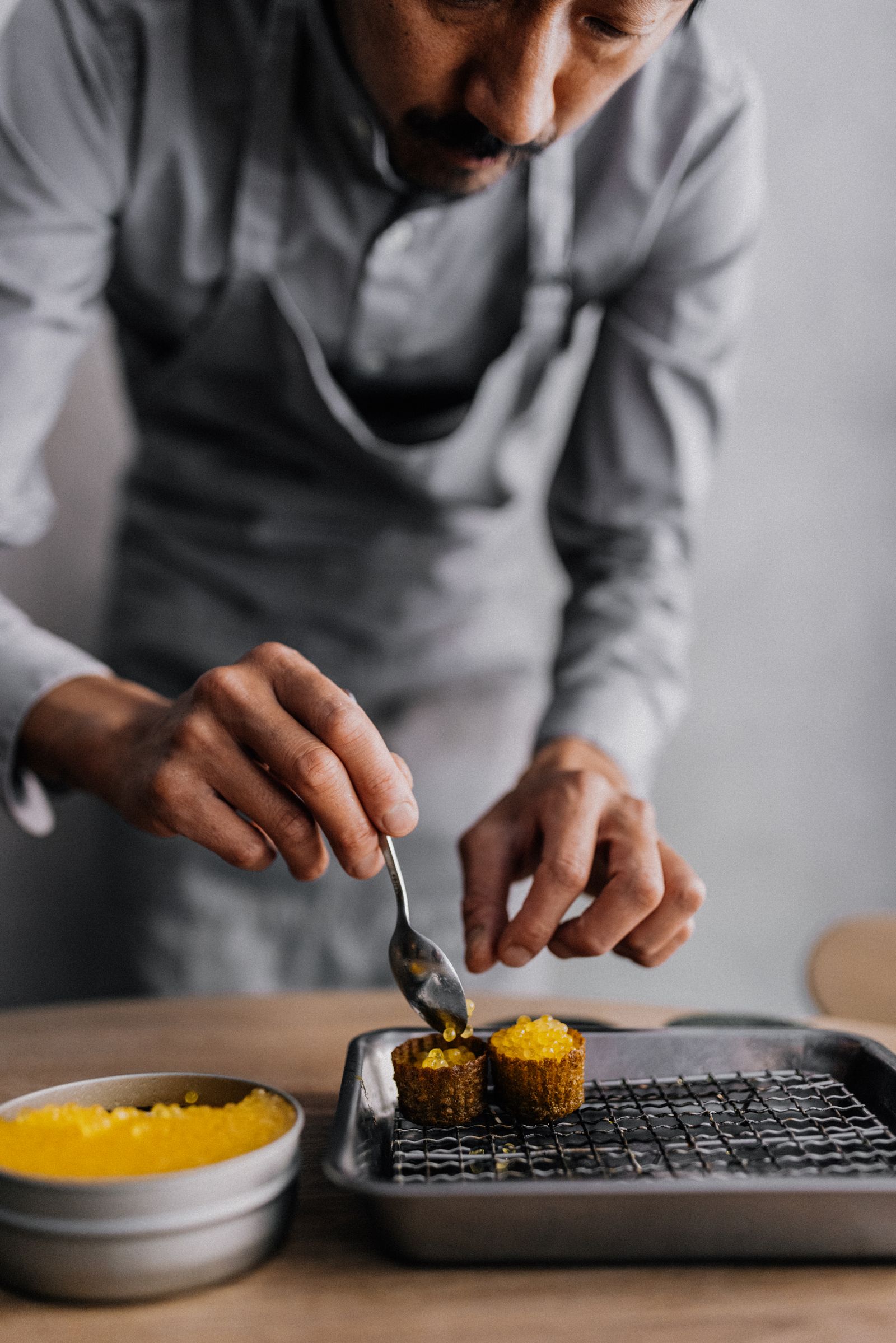 A chef or server presenting a gourmet dish to a diner at a set table.