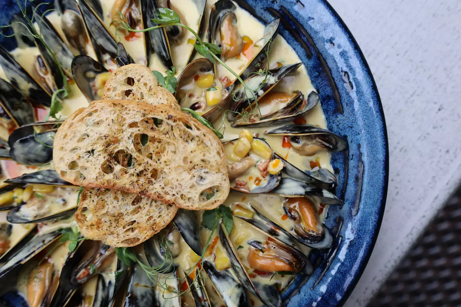 A gourmet plate of steamed mussels served in a coastal restaurant setting.