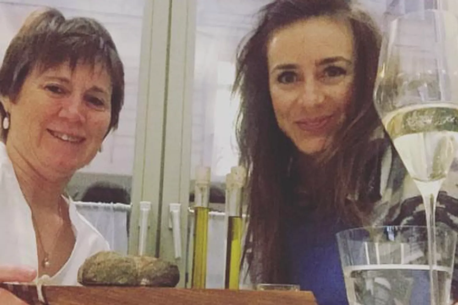 An elderly mother and her adult daughter smiling while eating at TIAN restaurant in Vienna, Austria.