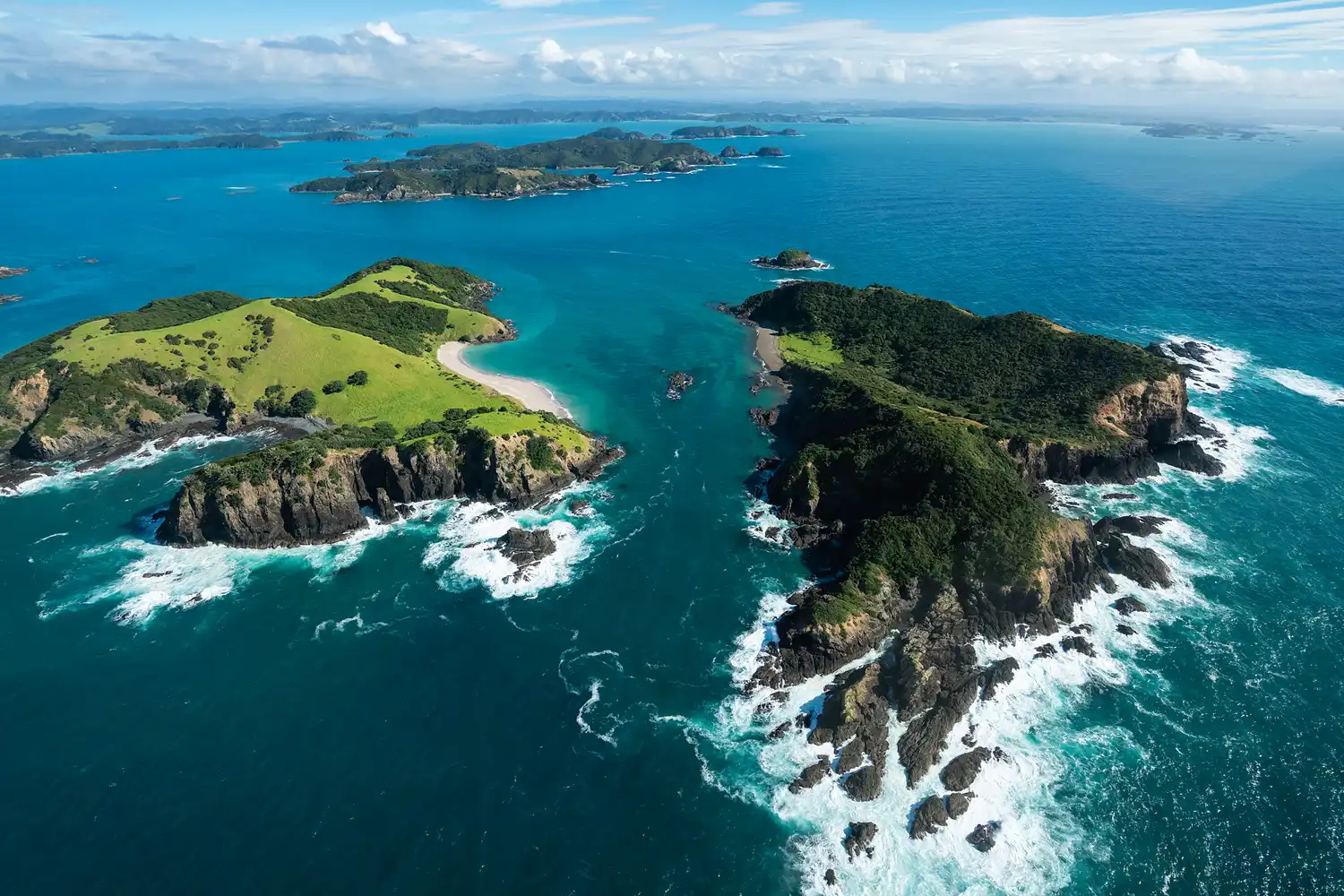 Aerial view of the lush green islands and blue waters of the Bay of Islands, New Zealand.
