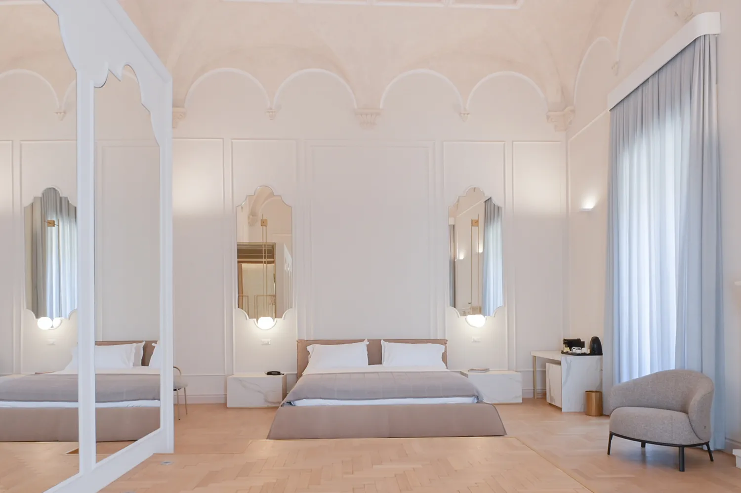 Luxury hotel suite interior in Lecce featuring star-vaulted stone ceilings and elegant bedding.