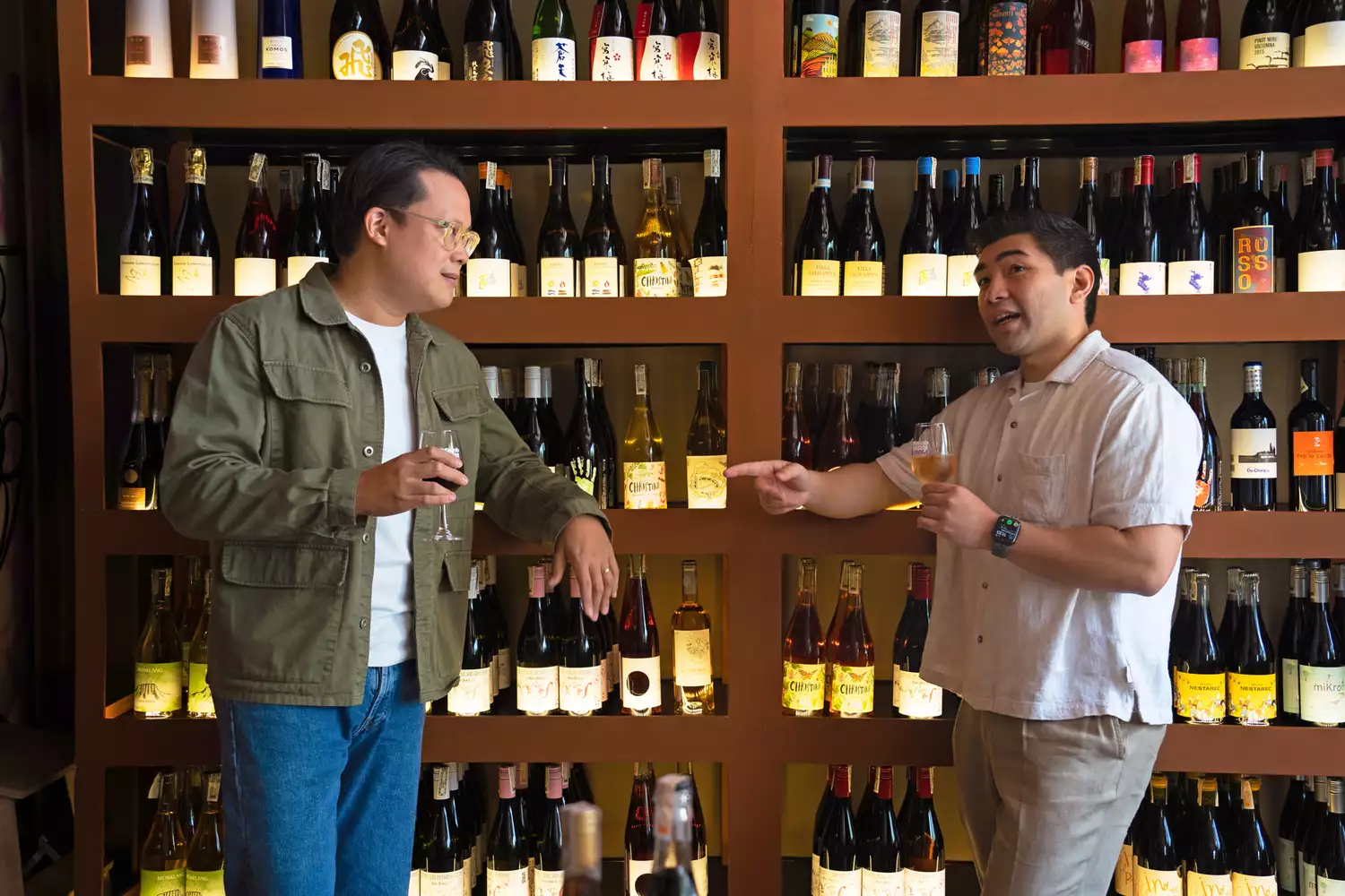 Joey Osmeña and Paolo Monasterio of Bombvinos standing in front of shelves filled with natural wine bottles.
