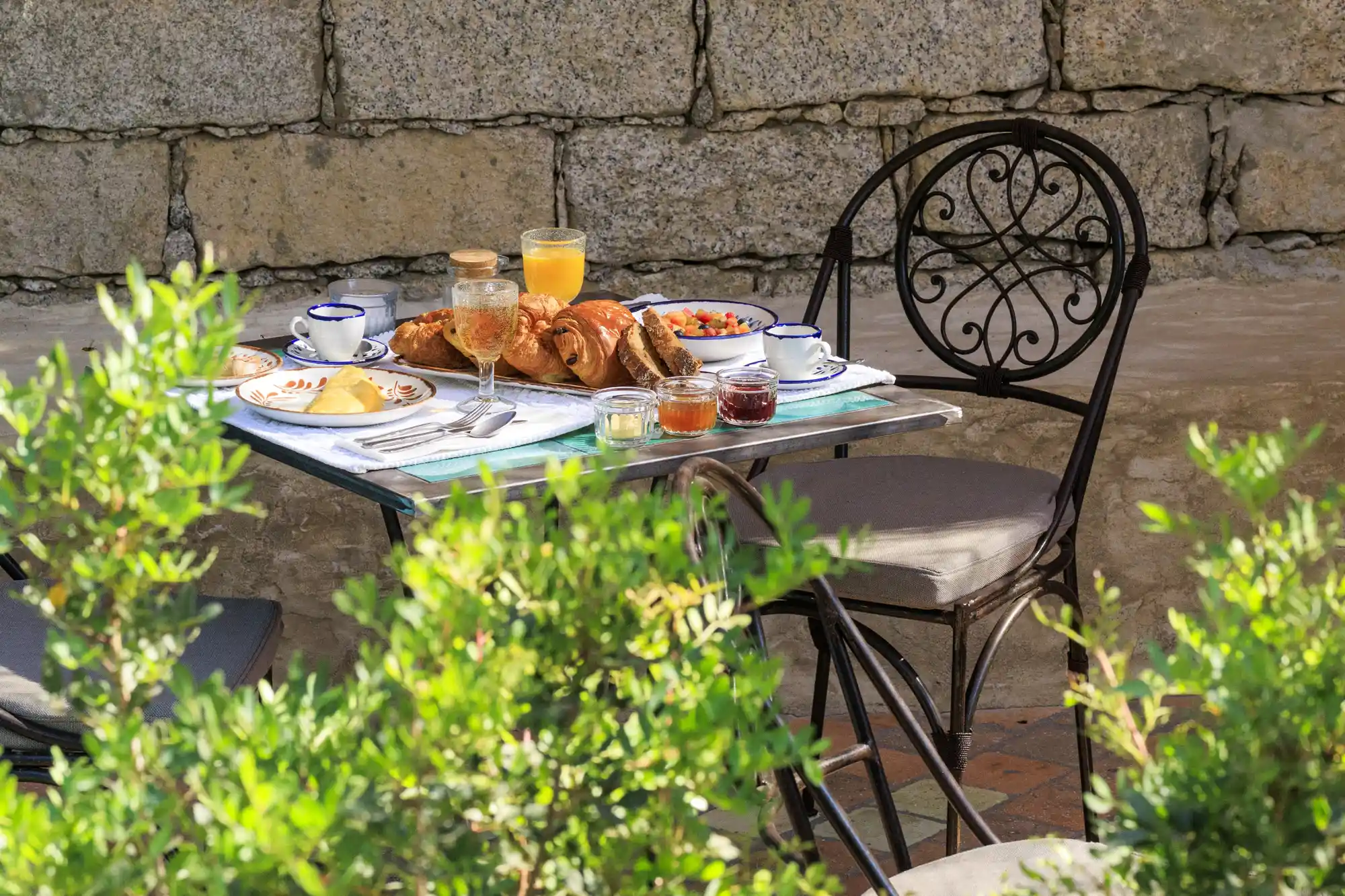 An outdoor breakfast table set with fresh food overlooking a lush Corsican garden.