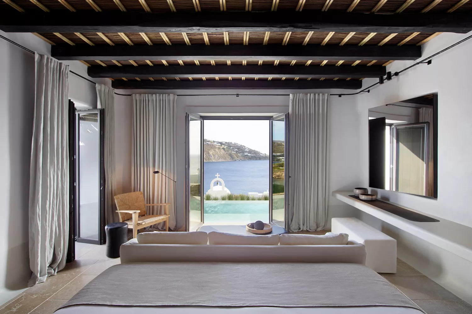 A modern guest room at Kalesma Mykonos with a view of the sea.
