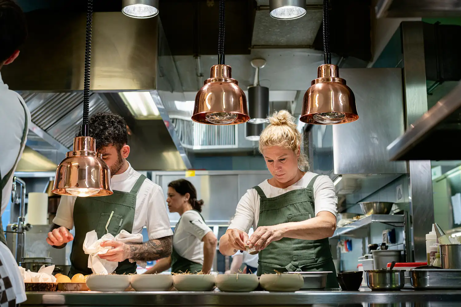 Chefs working in a busy, modern professional kitchen environment.