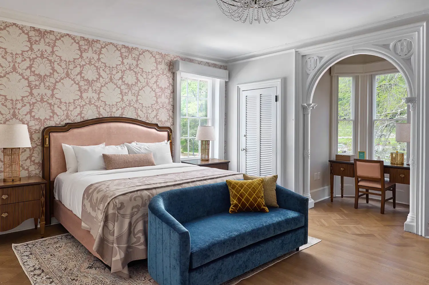 The Howland Suite showing a luxurious bedroom setup with blue accents and an arched doorway.