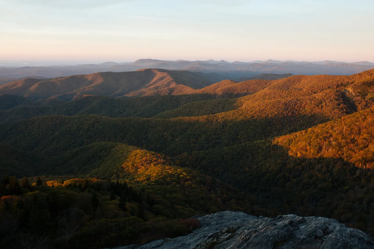 Lush mountain range with rolling hills and trees viewed during a golden sunset near Asheville.
