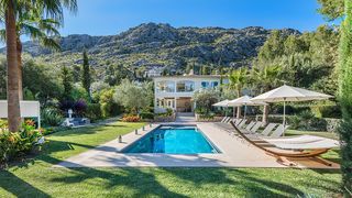 Aerial view of a contemporary villa with a large infinity swimming pool surrounded by lush landscaping in Mallorca.