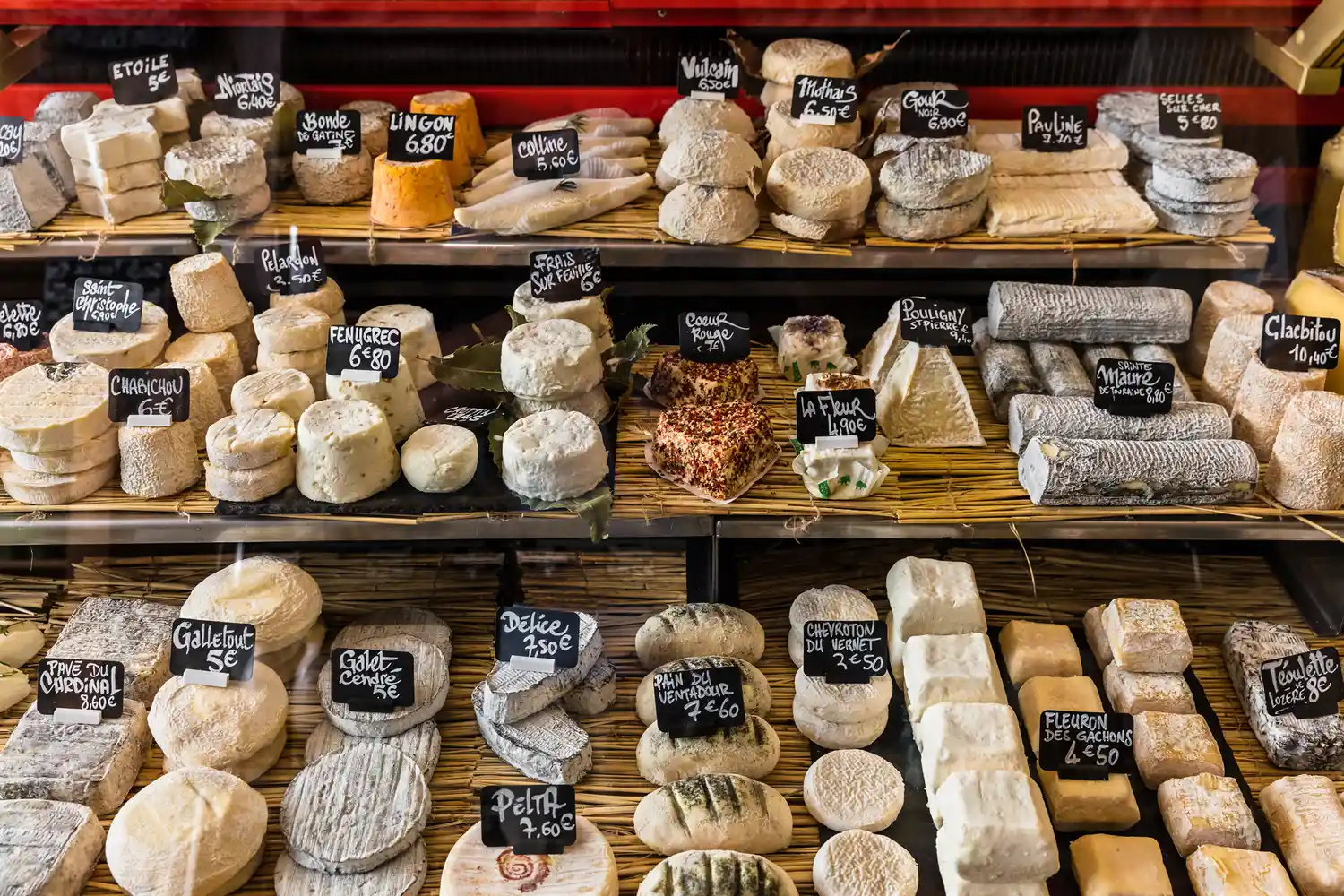 A variety of French cheeses displayed on shelves in a local delicatessen.
