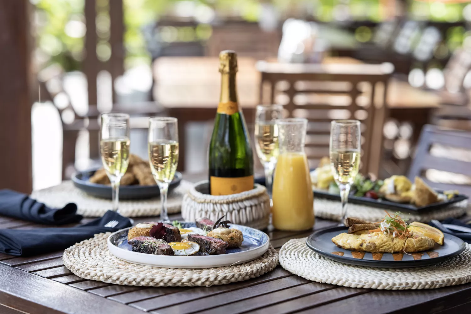A spread of Caribbean seafood dishes and cocktails on a table overlooking the ocean.
