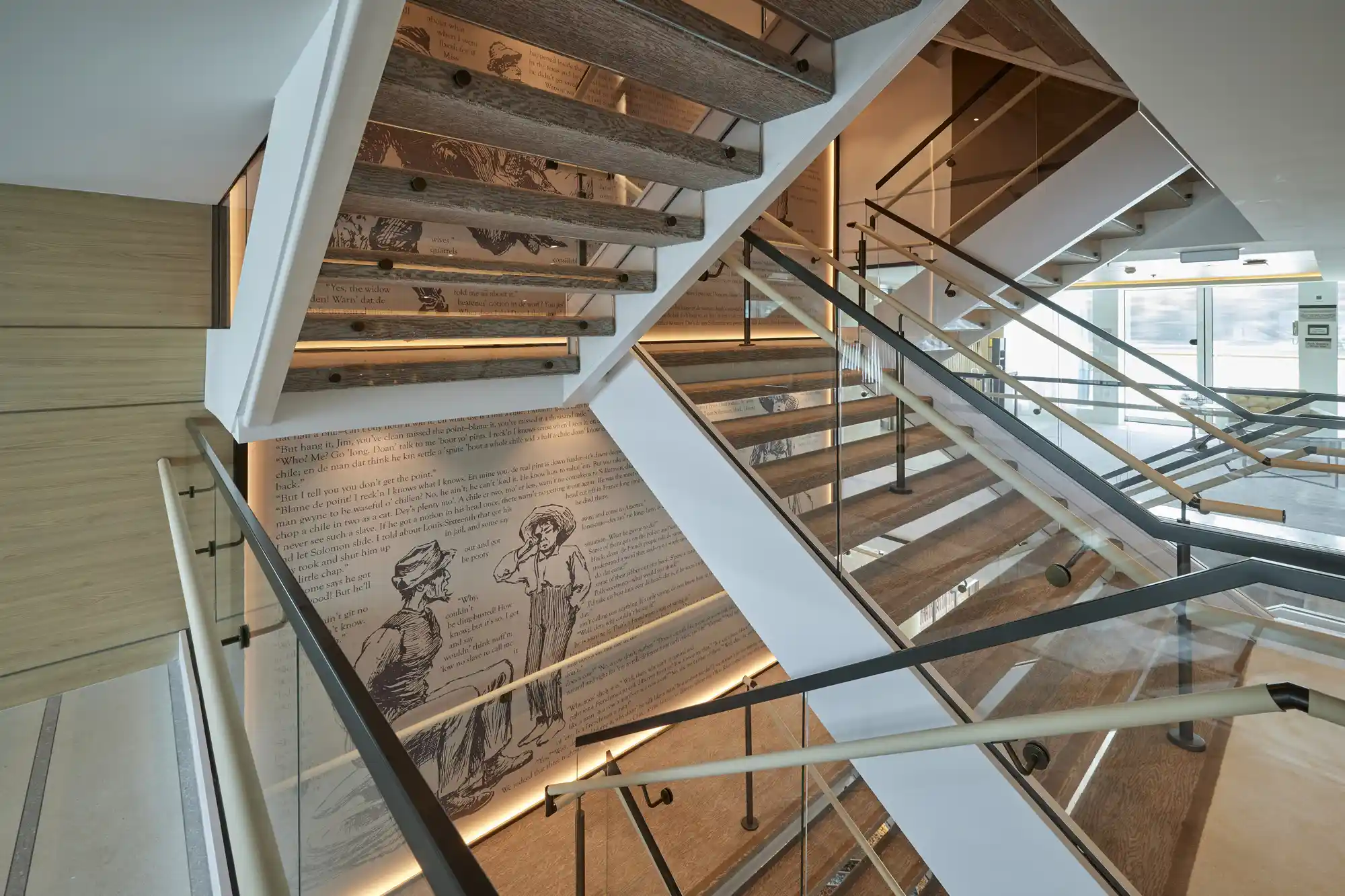 Modern interior of a luxury riverboat featuring glass railings, elegant staircases, and contemporary artwork.