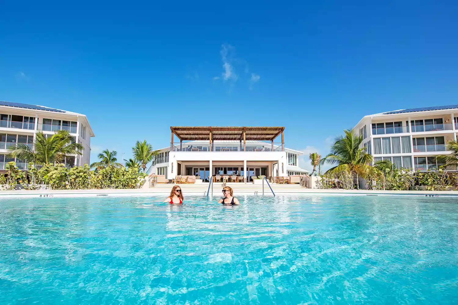 Guests lounging by the infinity pool at Salterra South Caicos with ocean views.