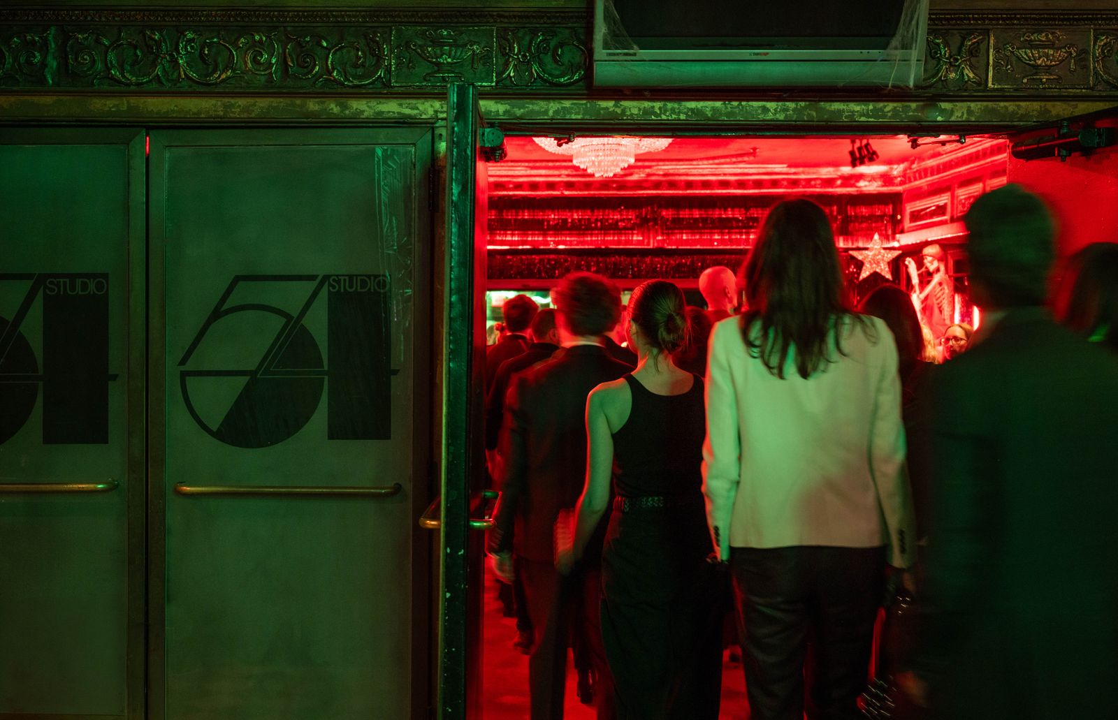 A woman in a club setting looking away from the camera amidst night life energy.