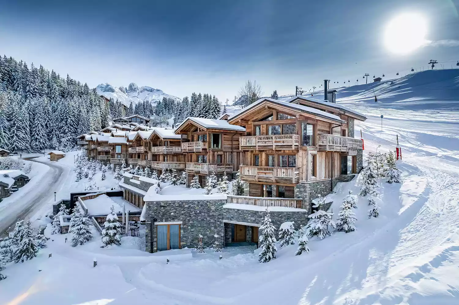 Modern luxury hotel building with wood and stone architecture situated directly on the snowy slopes.