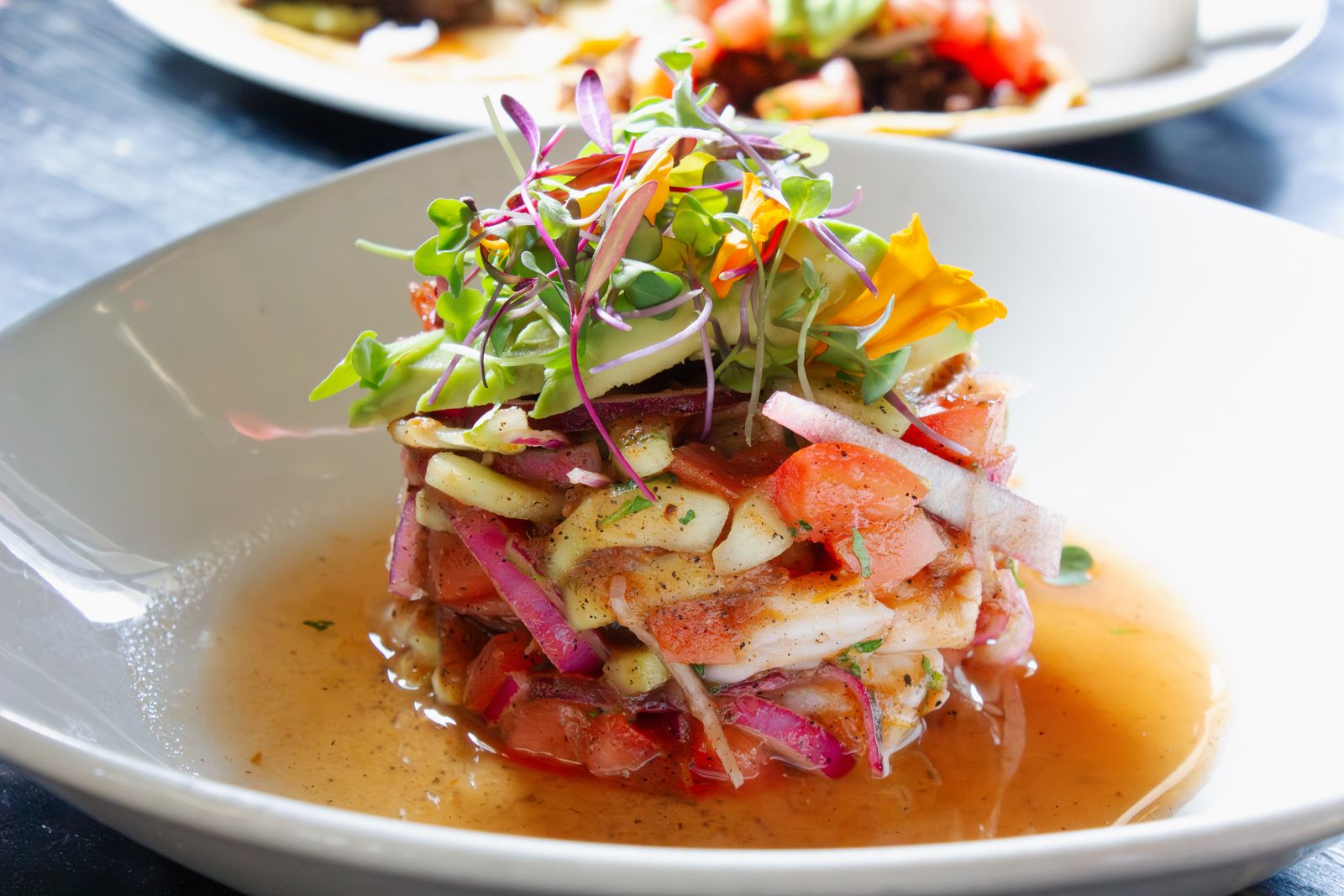 A close-up of a modern, vibrant plated dish featuring fresh ingredients and intricate garnishes.