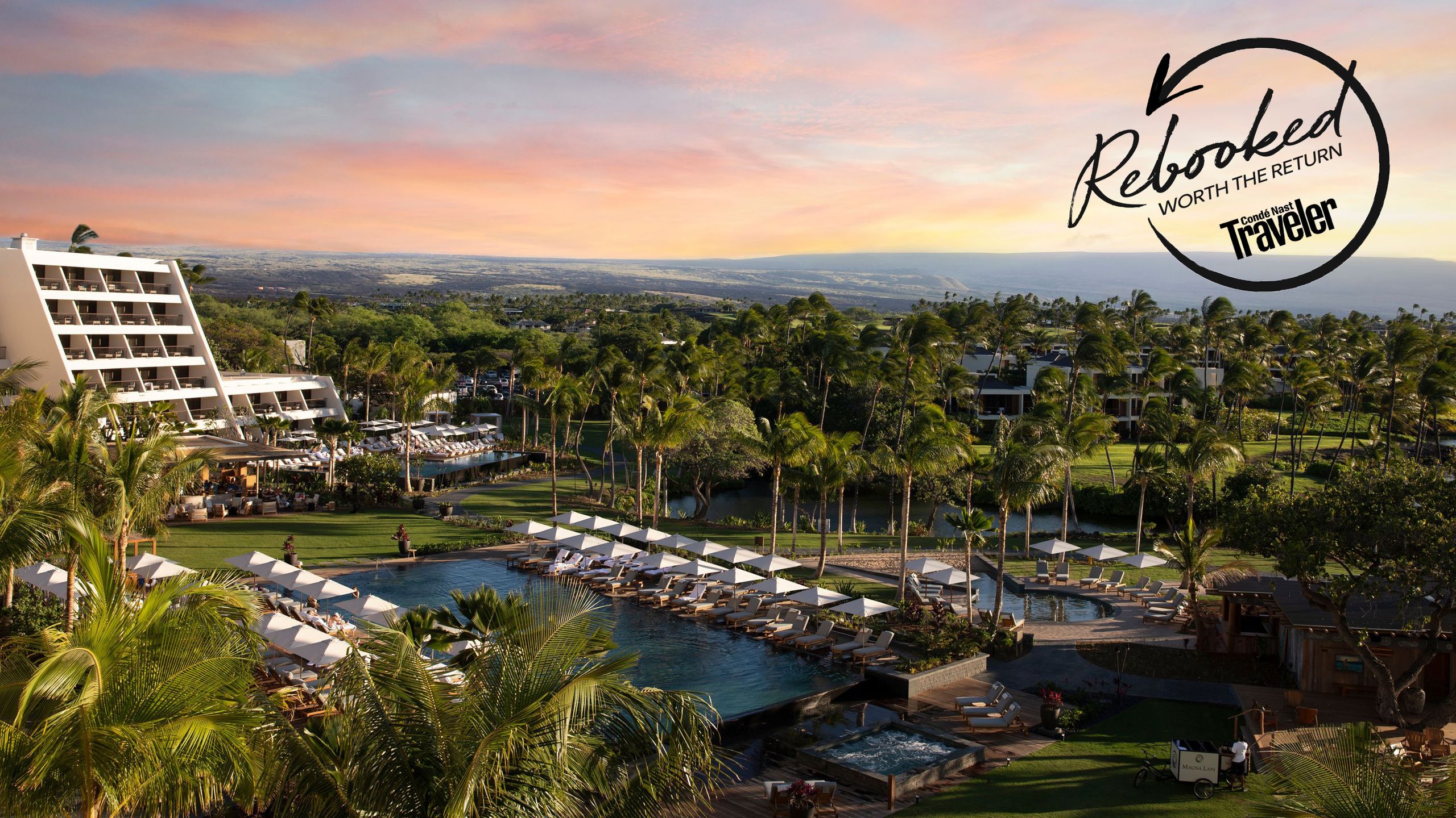 A wide-angle shot of the resort's swimming pool area under the summer sun with the waterfront in the background.