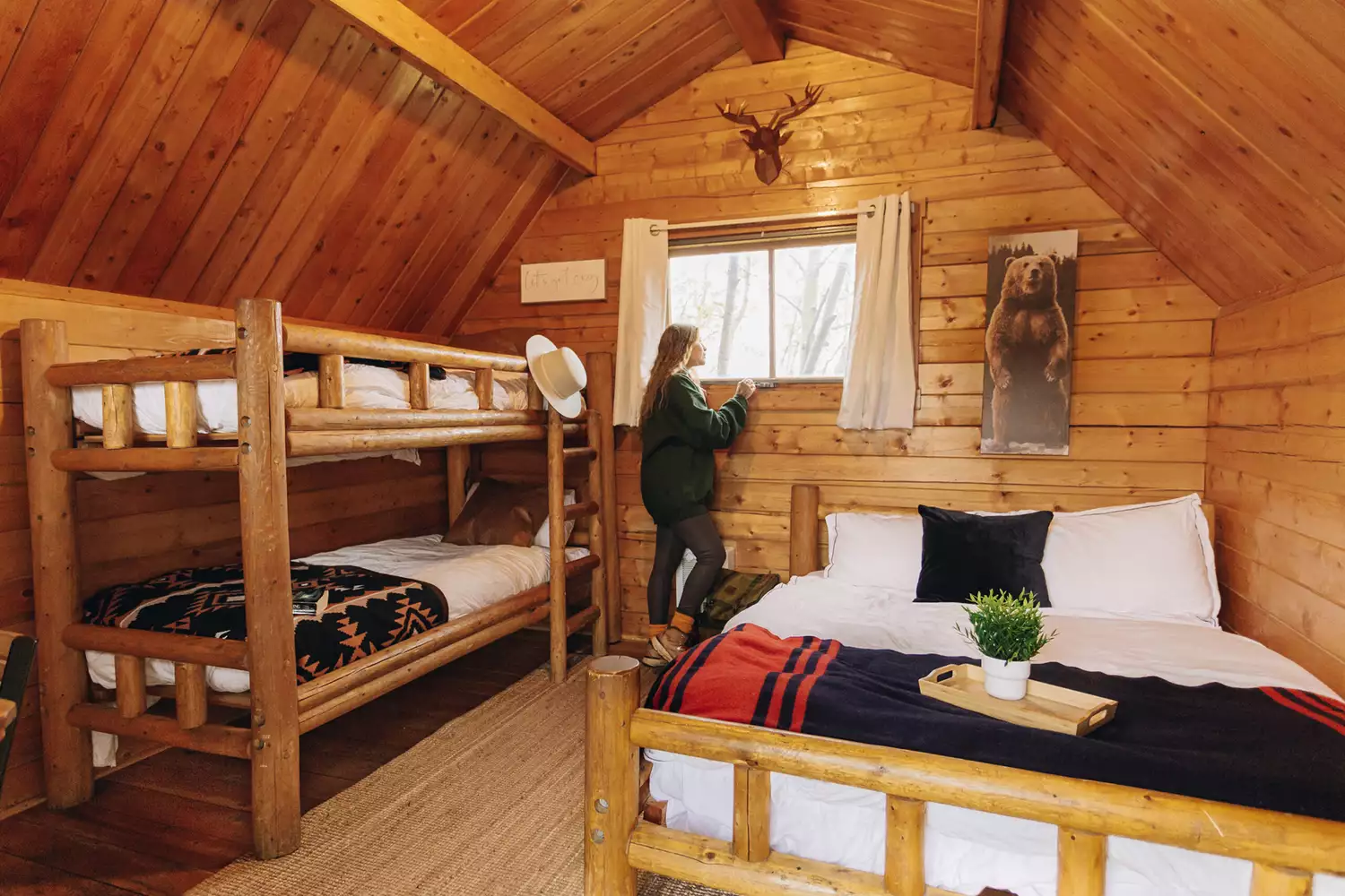 A bright, clean wooden interior of a rental cabin featuring bunk beds and rustic mountain decor.