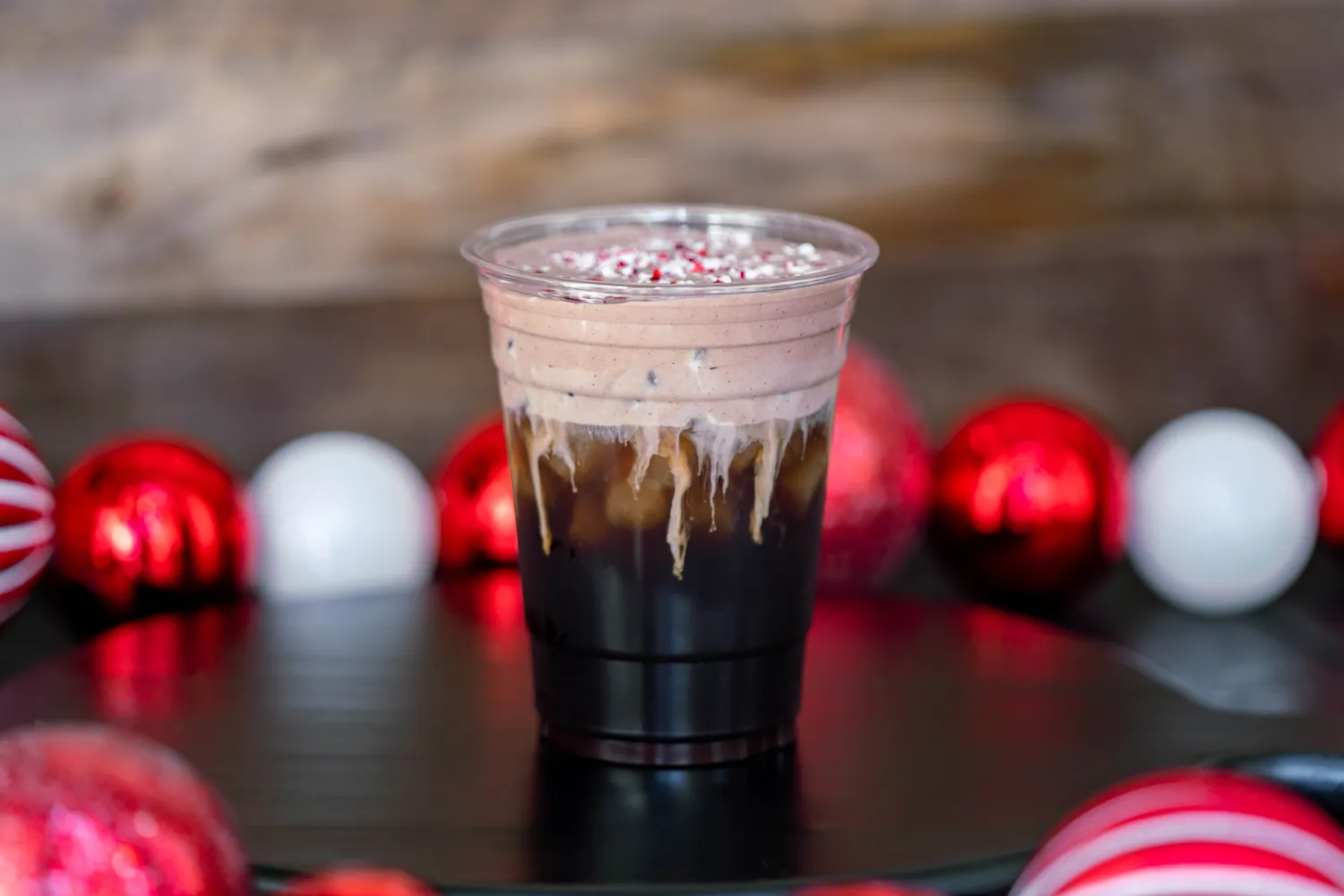 A festive holiday-themed drink in a clear cup surrounded by red and white ornaments.