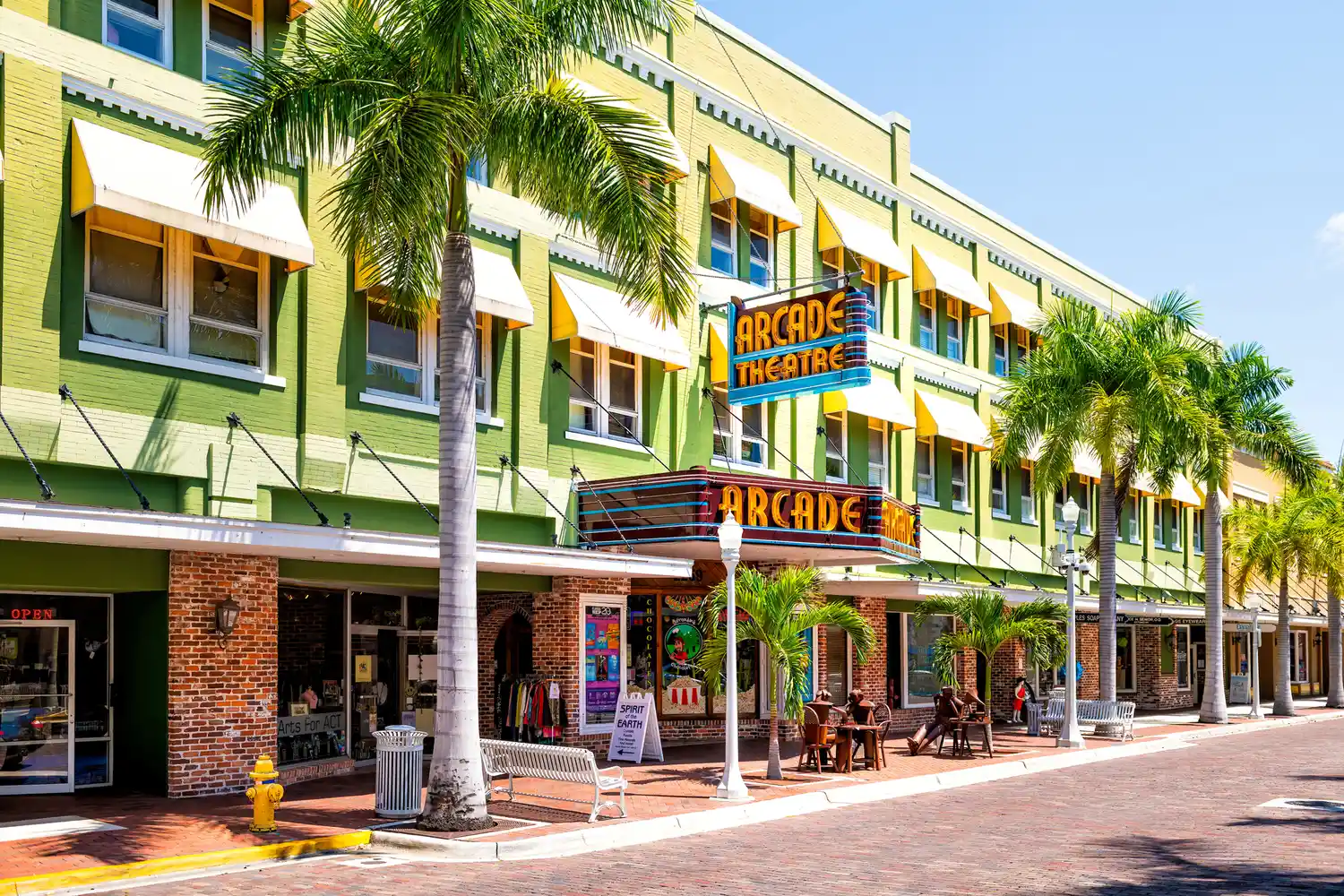 The historic Arcade Theatre building in downtown Fort Myers with outdoor seating and palm trees.