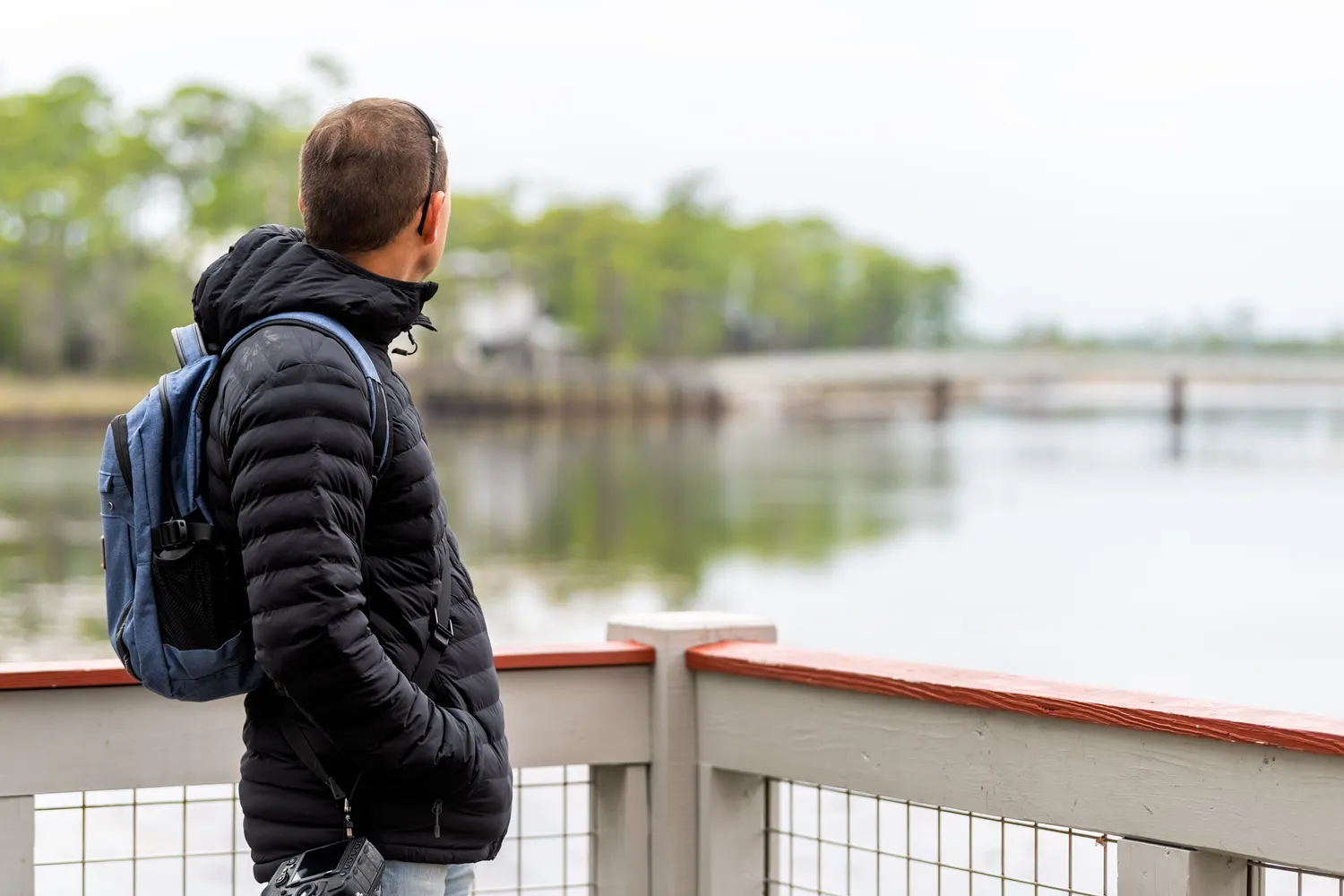 A visitor stands on a wooden boardwalk looking out over the water at Grayton Beach State Park.