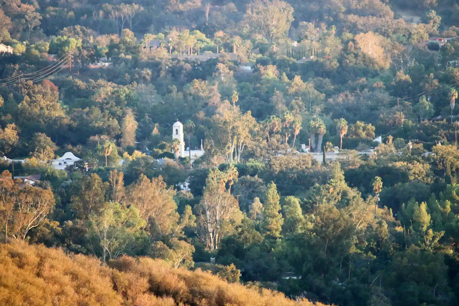 Aerial view of a town in a valley surrounded by dense green vegetation and mountains.
