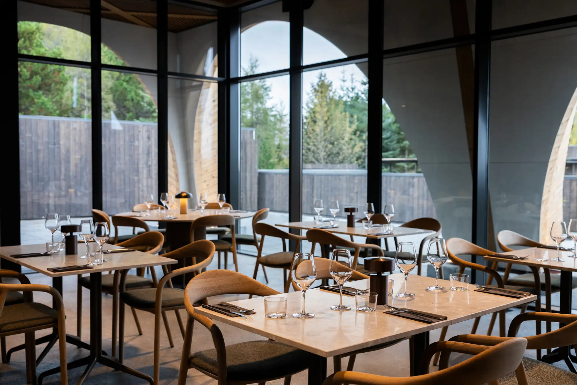 Interior of Ylja restaurant featuring modern furniture and large windows looking out onto trees.