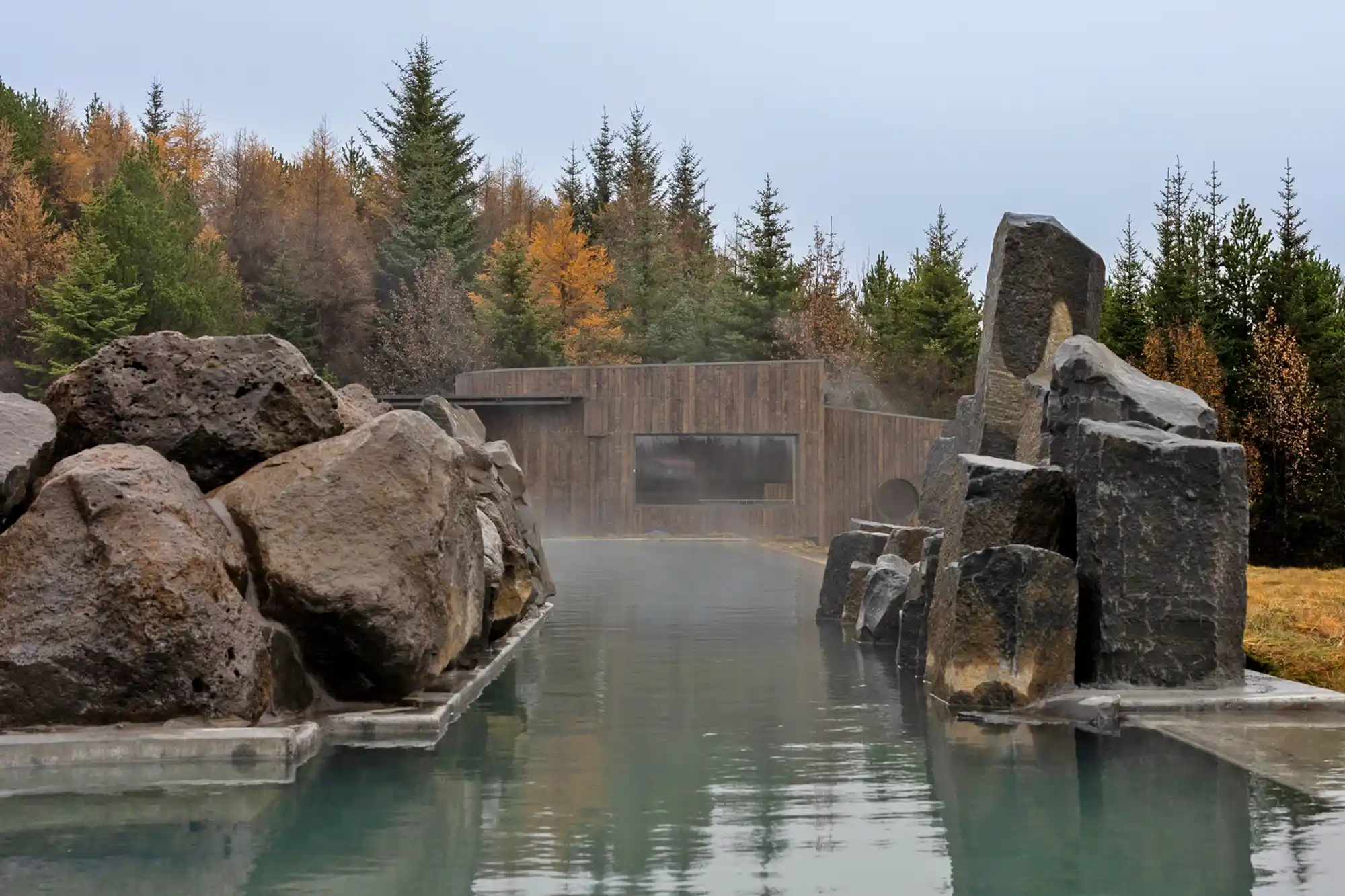 A social geothermal pool styled as a stone grotto with surrounding greenery.