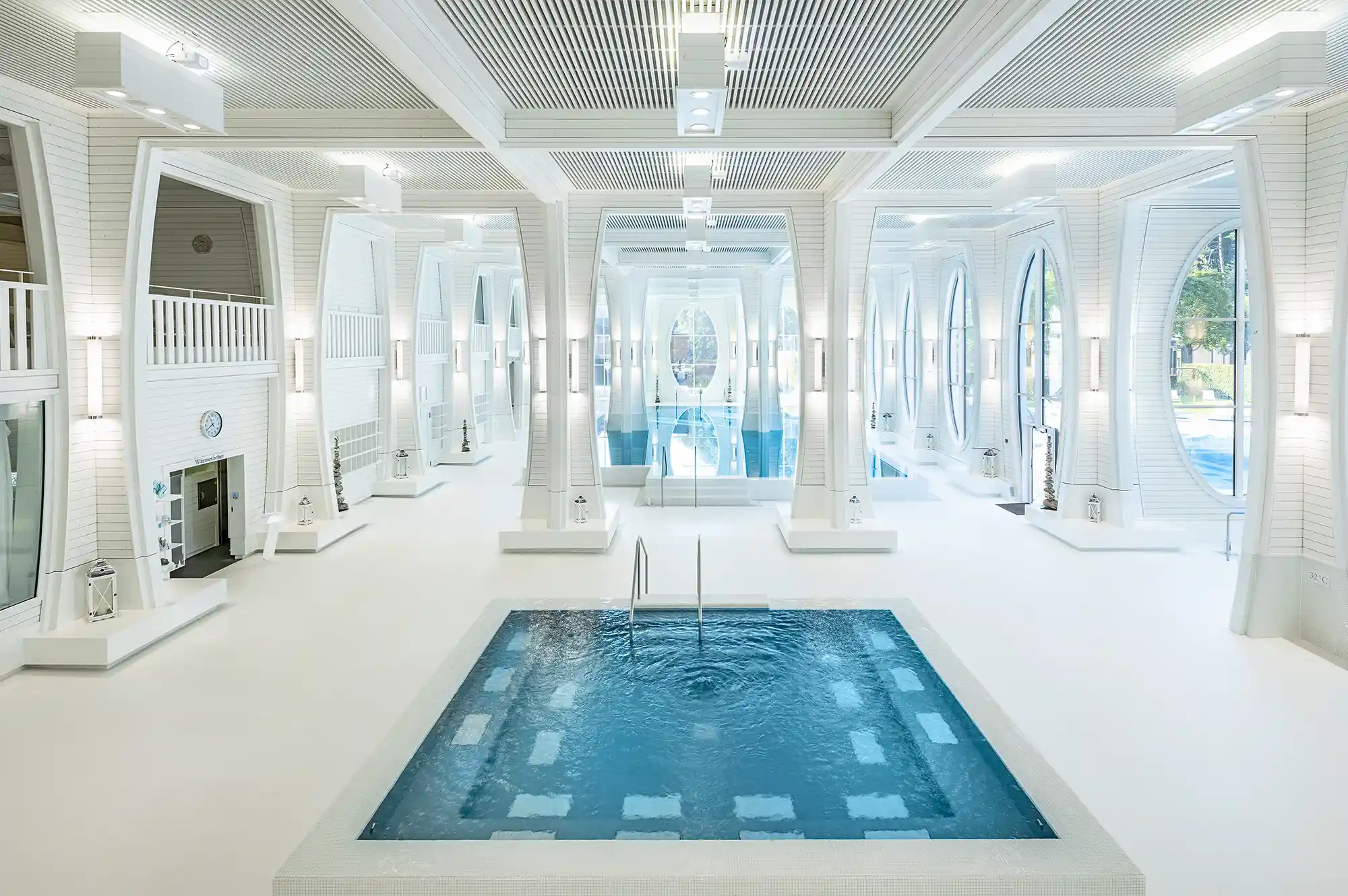 The historic Helena Bath with high arched windows and a serene indoor pool filled with blue thermal water.