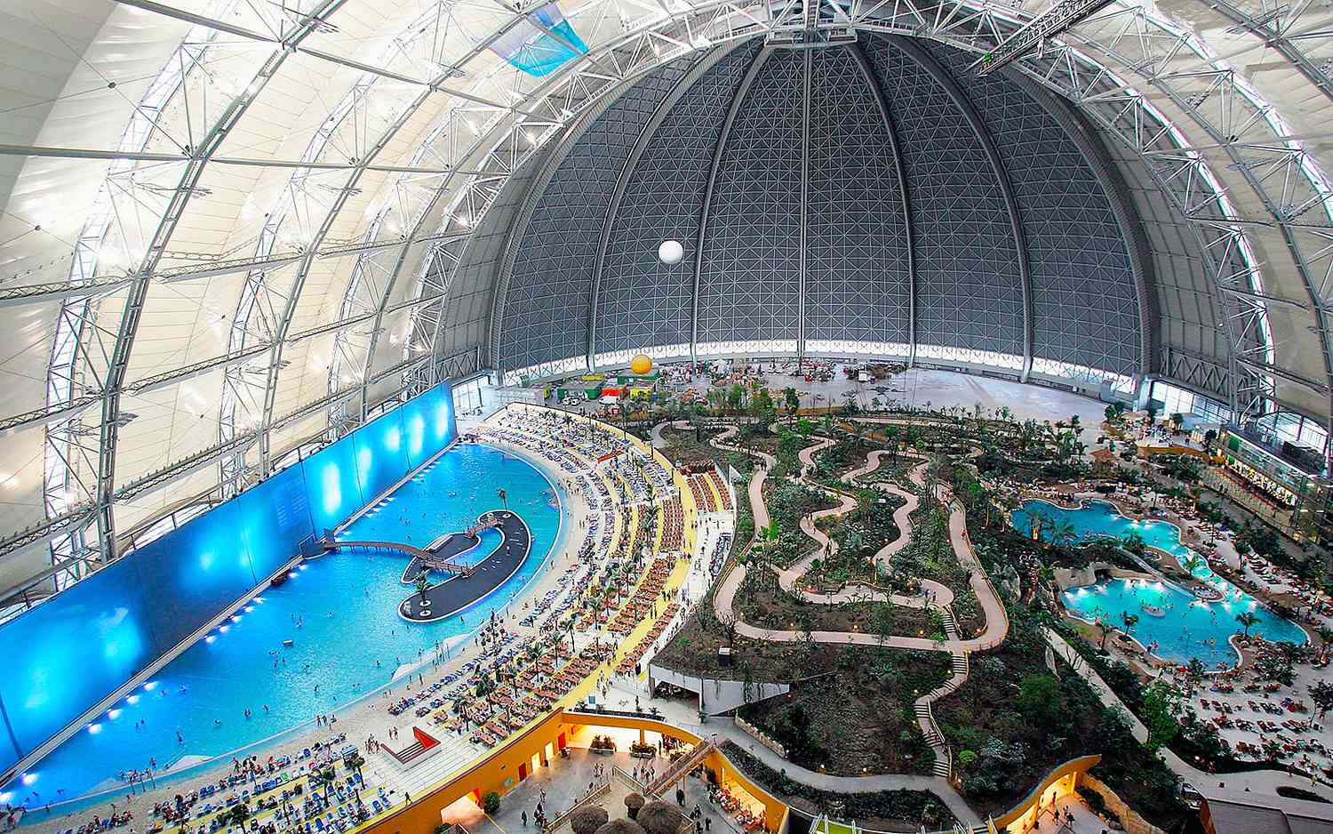 Wide shot of the lush indoor rainforest and lagoon area inside the Tropical Islands dome.